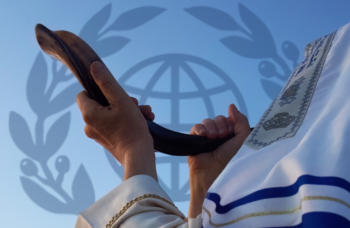 man covered with tallit appearing to blow a shofar