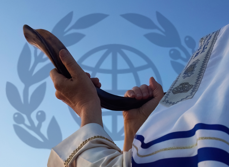 man covered with tallit appearing to blow a shofar